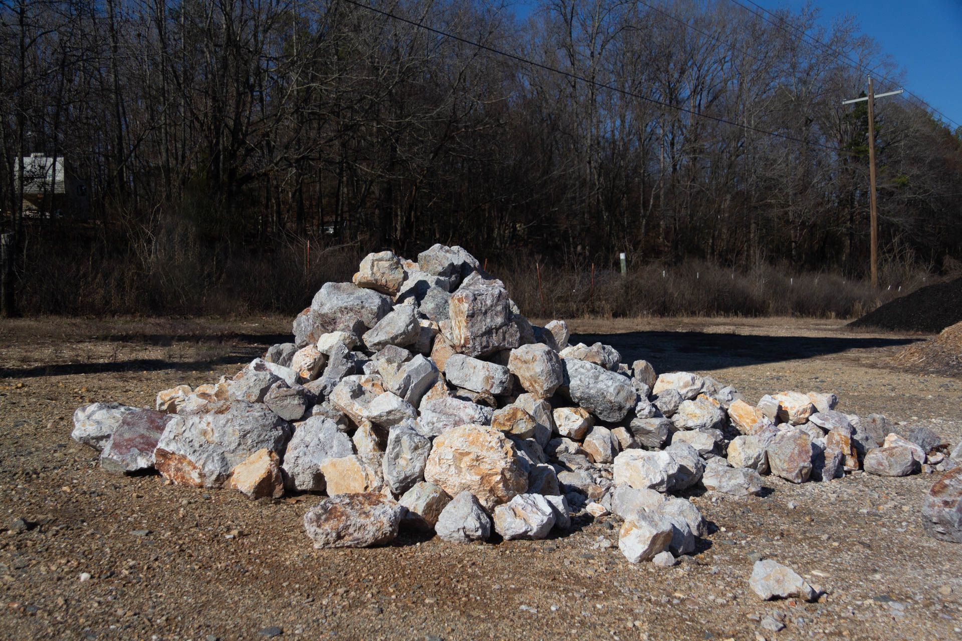A pile of rocks is sitting in the middle of a dirt field.