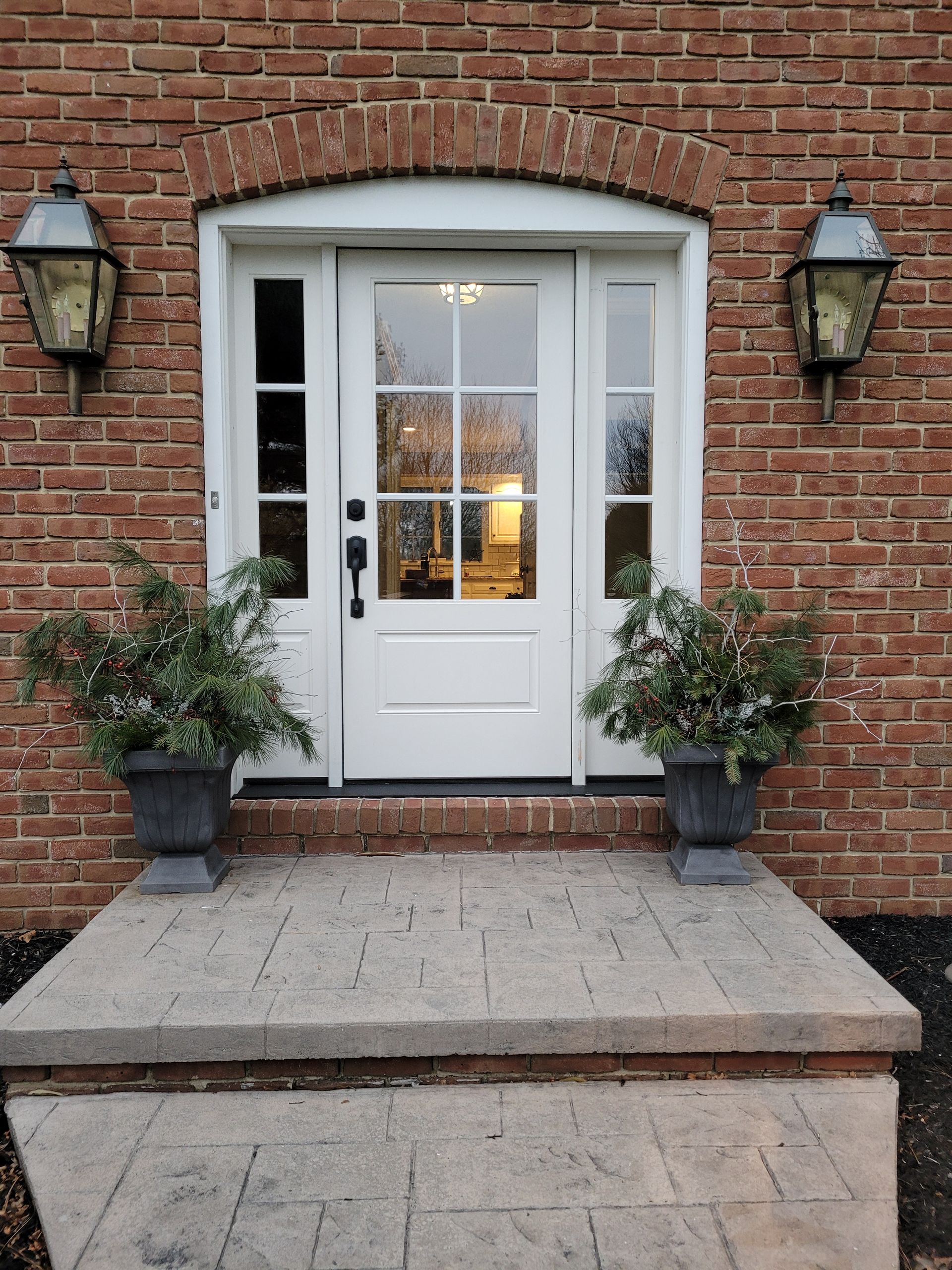 A brick building with a white door and potted plants in front of it