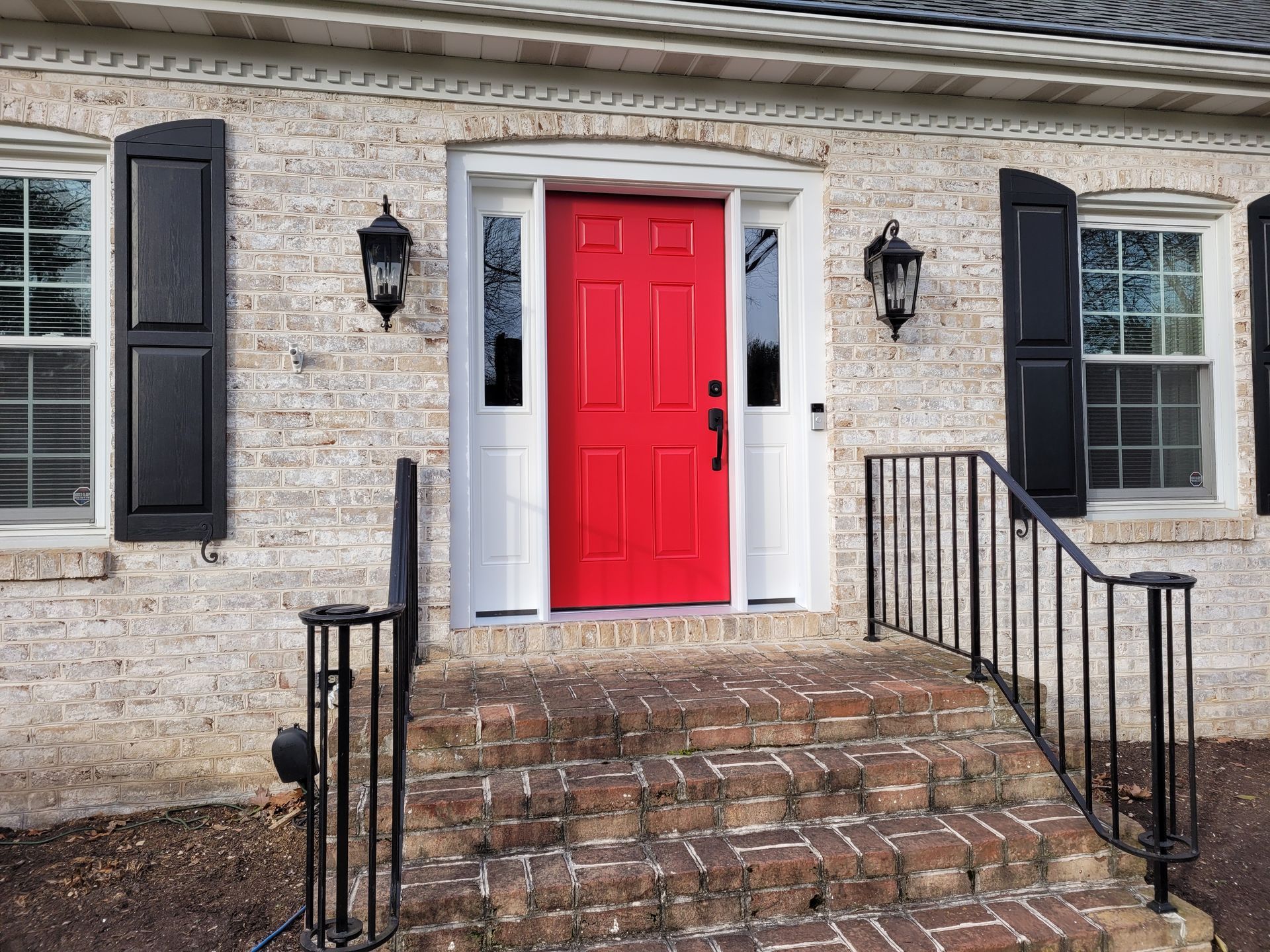 A brick house with a red door and black shutters
