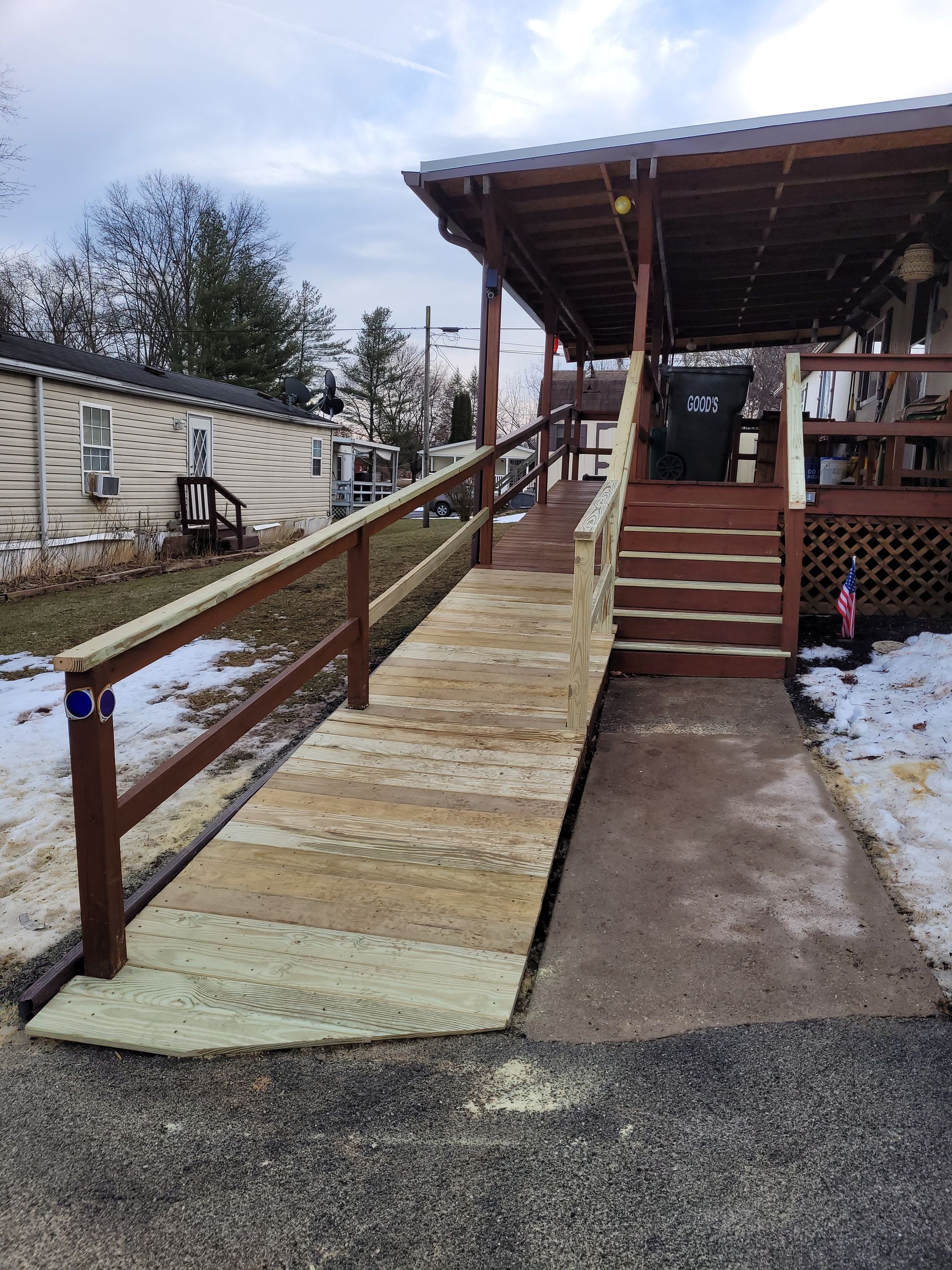 A wooden ramp leading to a house with stairs and a wooden railing.