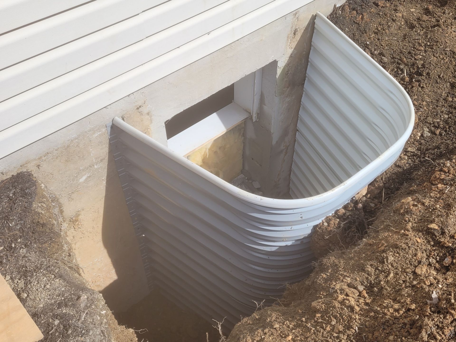 A window well in the ground next to a house