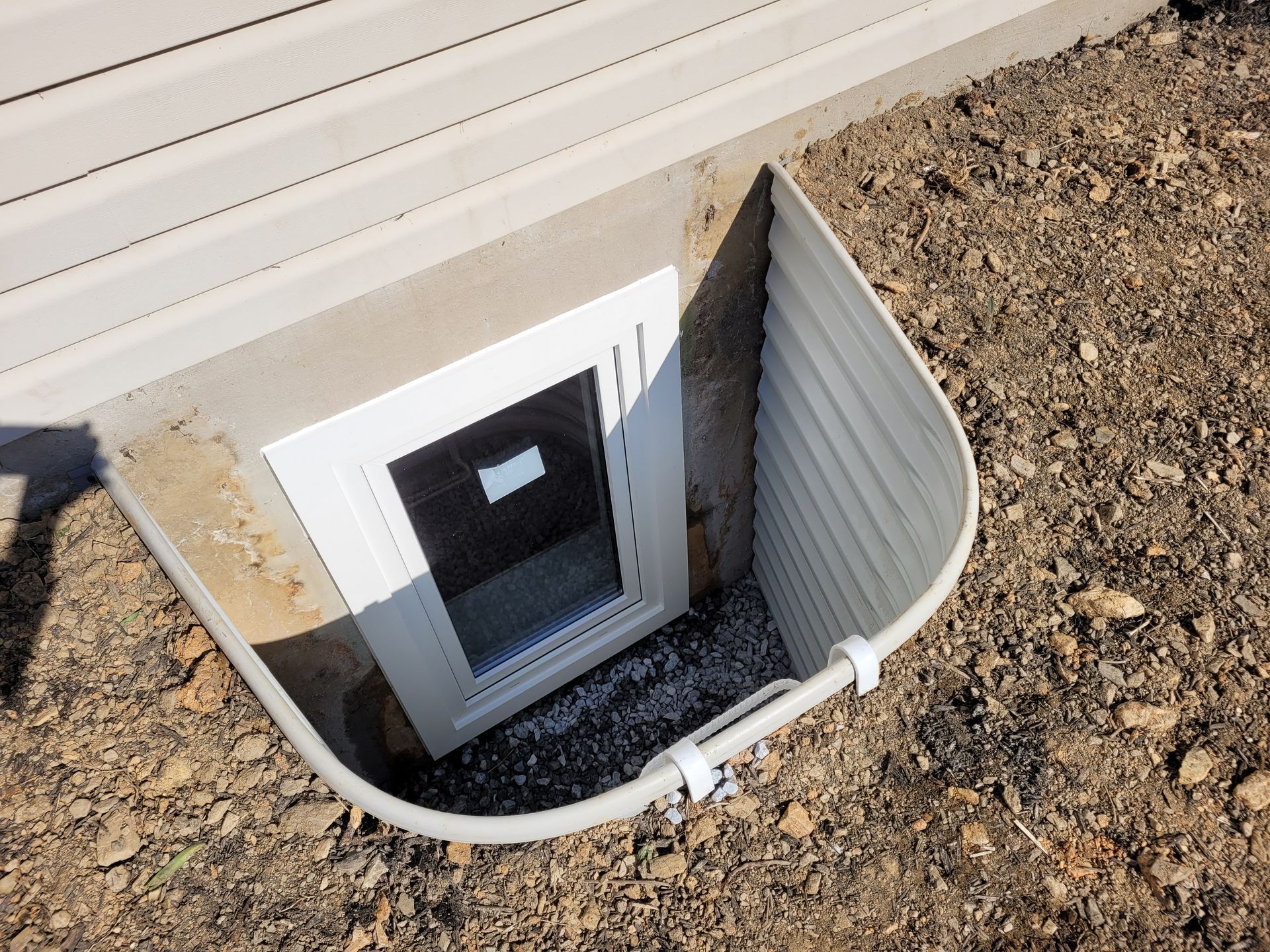 A window in the ground next to a house.