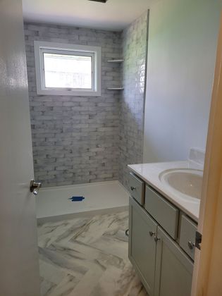 A bathroom with a sink and a walk in shower.