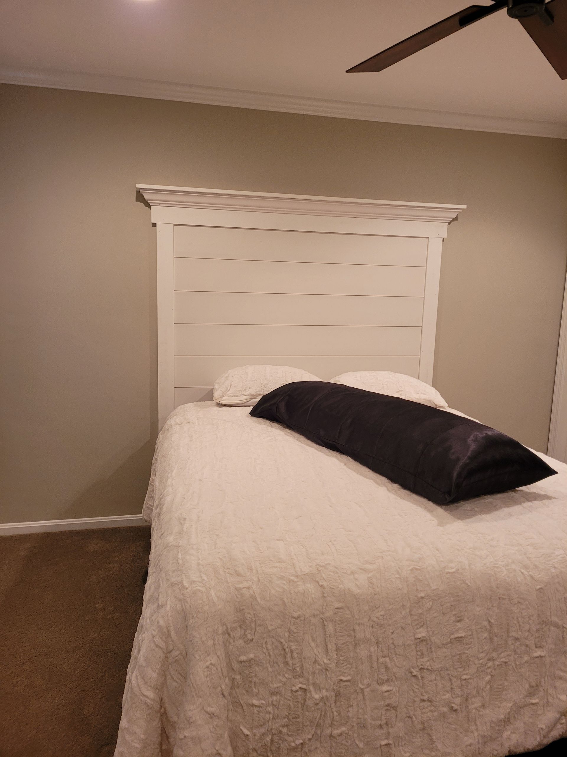 A bedroom with a bed and a ceiling fan