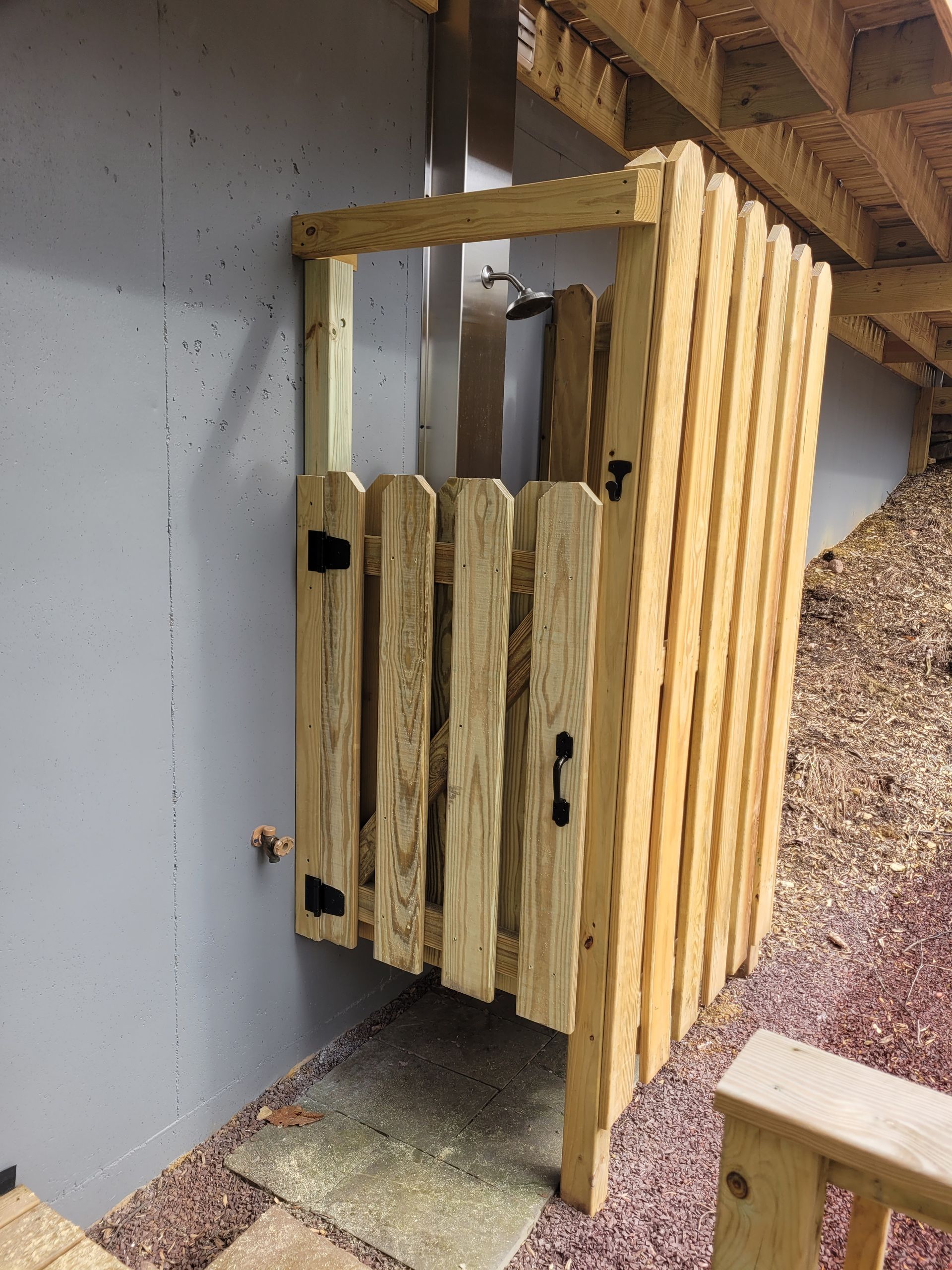 A wooden fence with a door is sitting next to a wall.