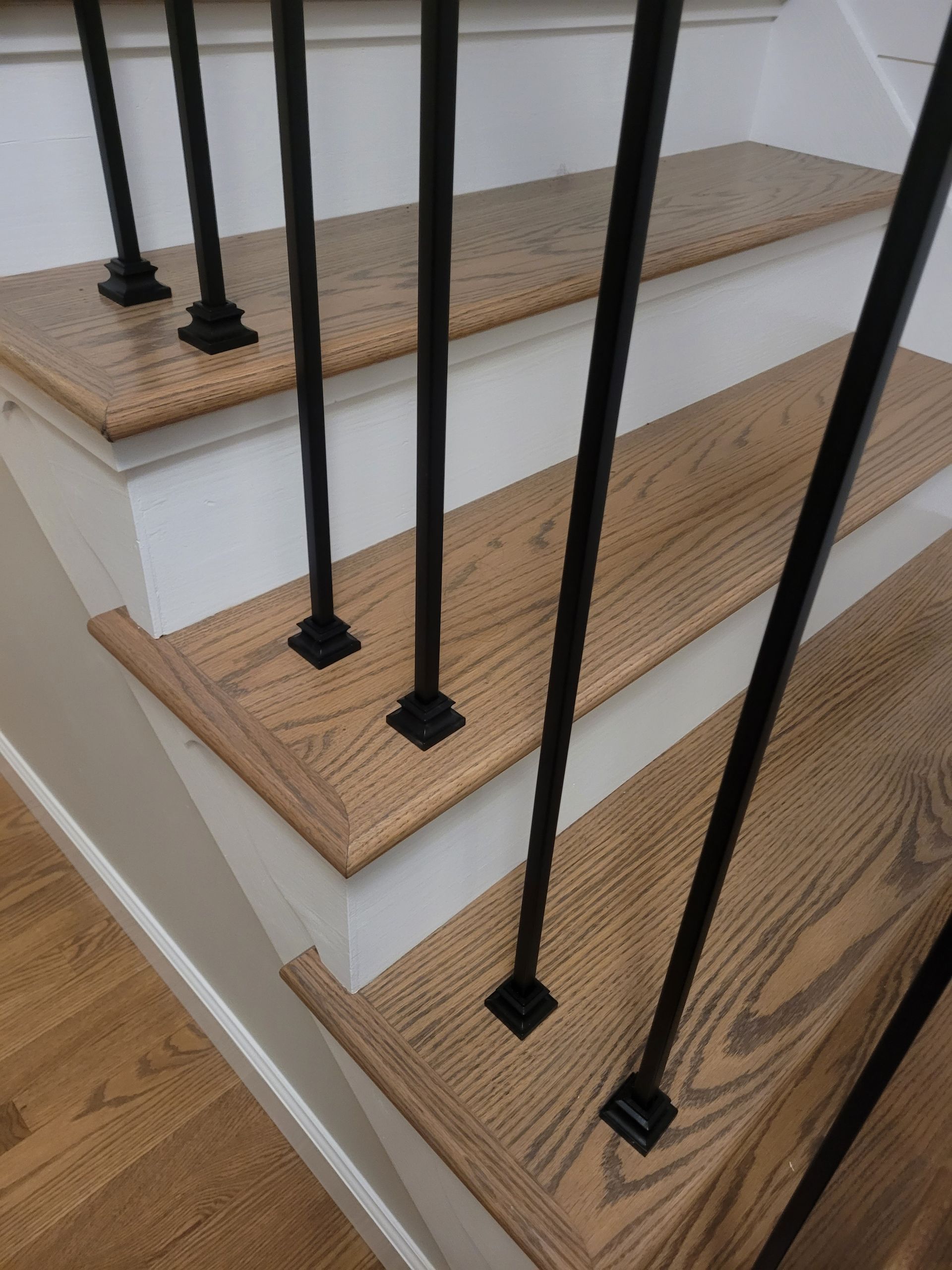A close up of a staircase with wooden steps and black railing
