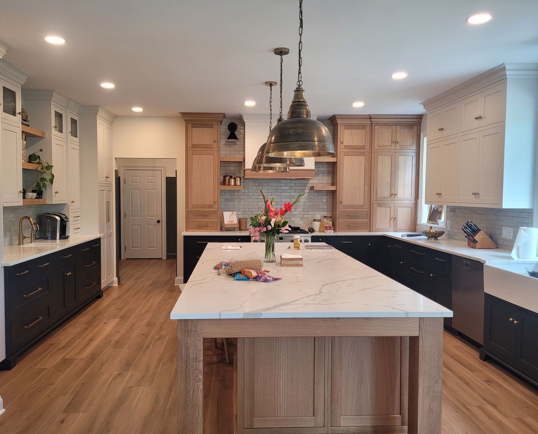 A kitchen with white cabinets , stainless steel appliances , a large island , a sink and a microwave.