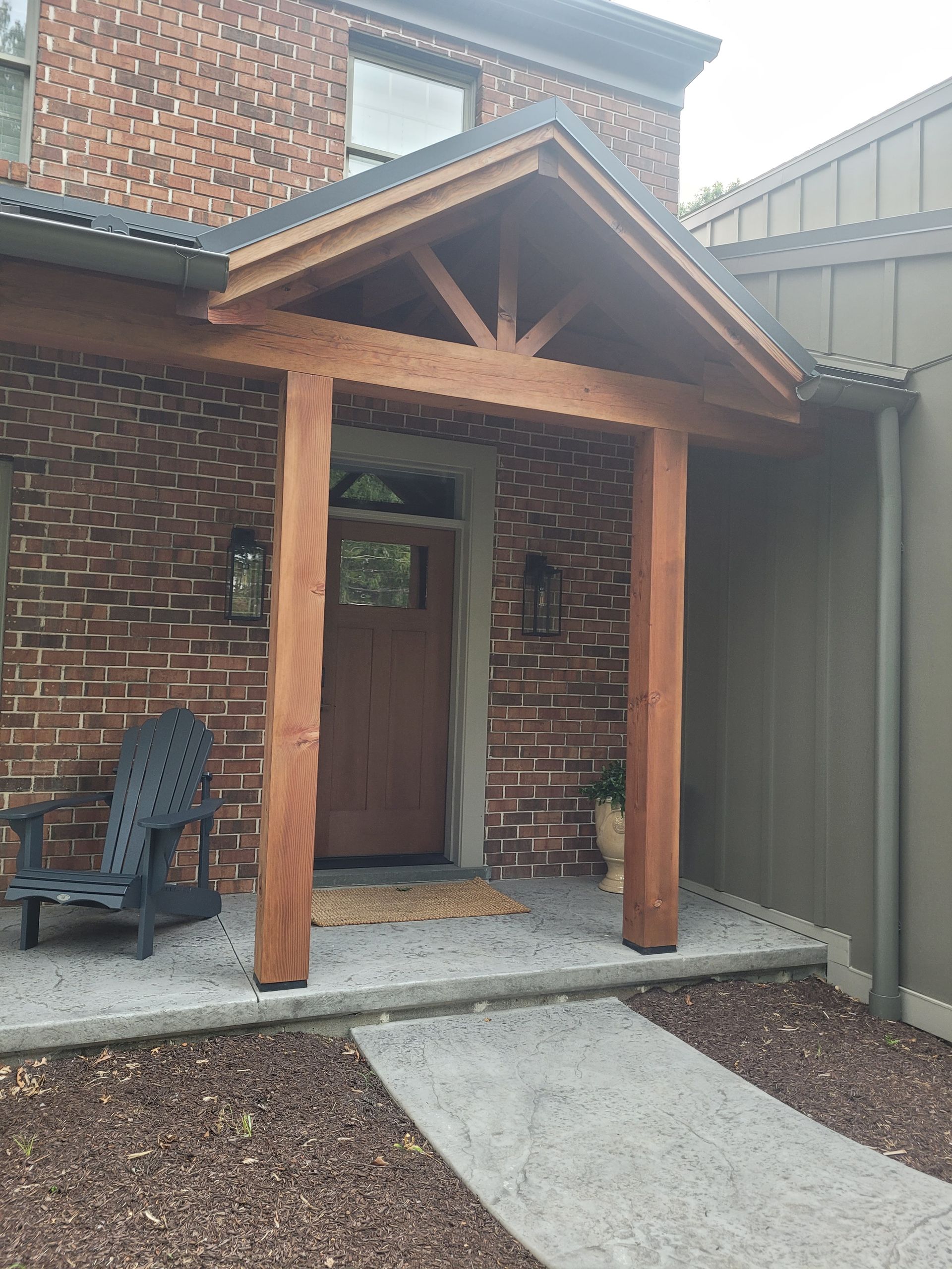 A brick house with a wooden porch and a chair in front of it.