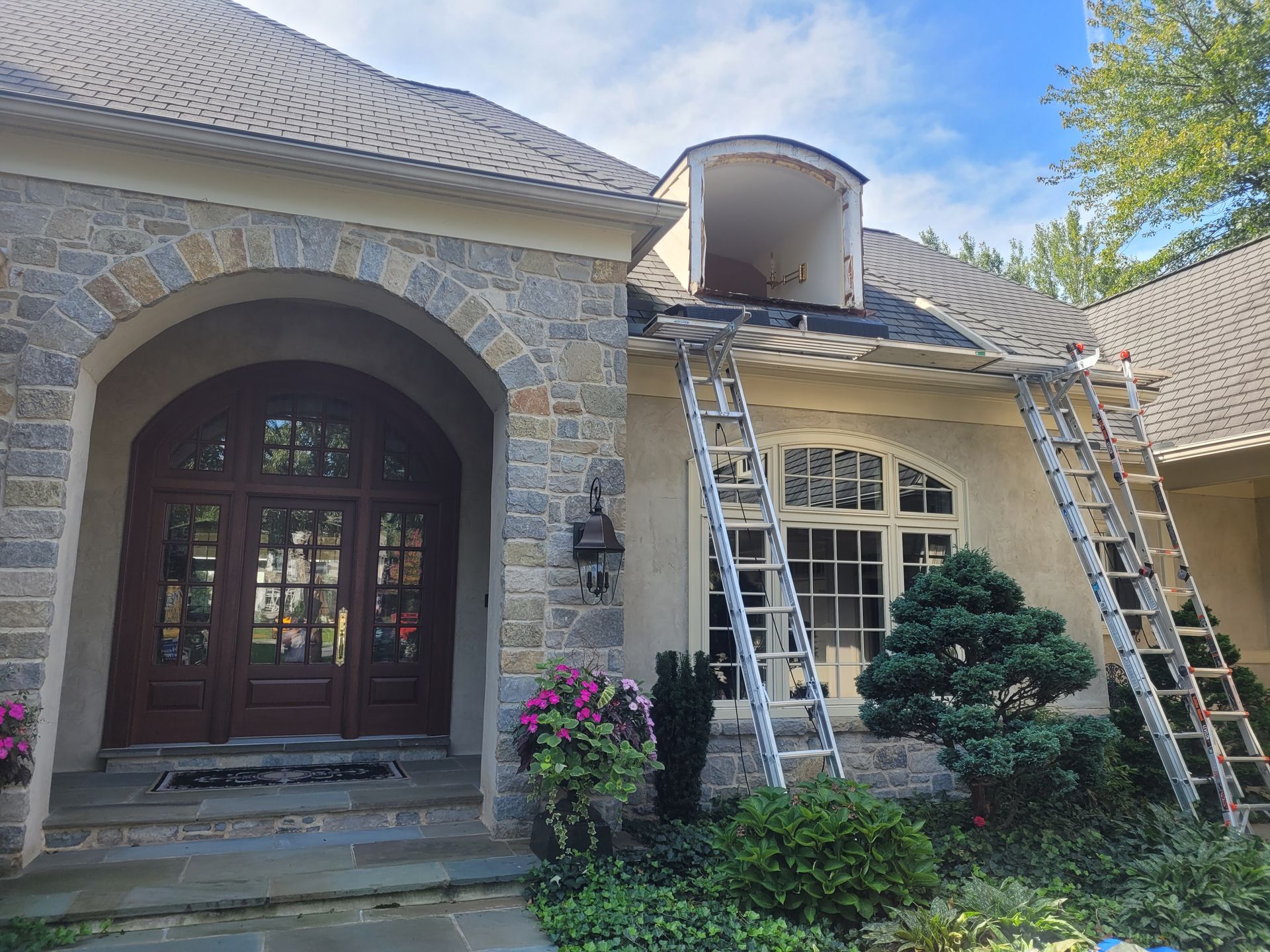 A large stone house with a roof that is being painted.