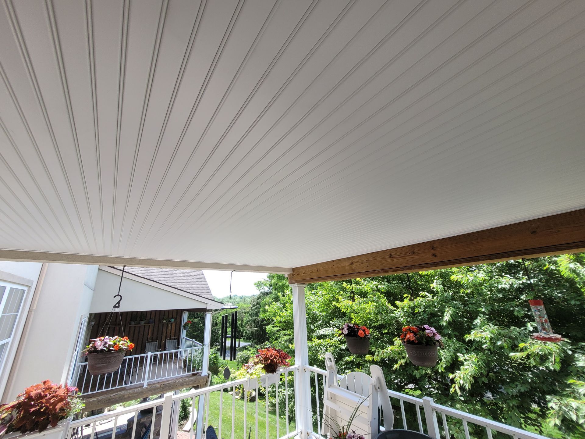 A balcony with a white ceiling and potted plants on it.