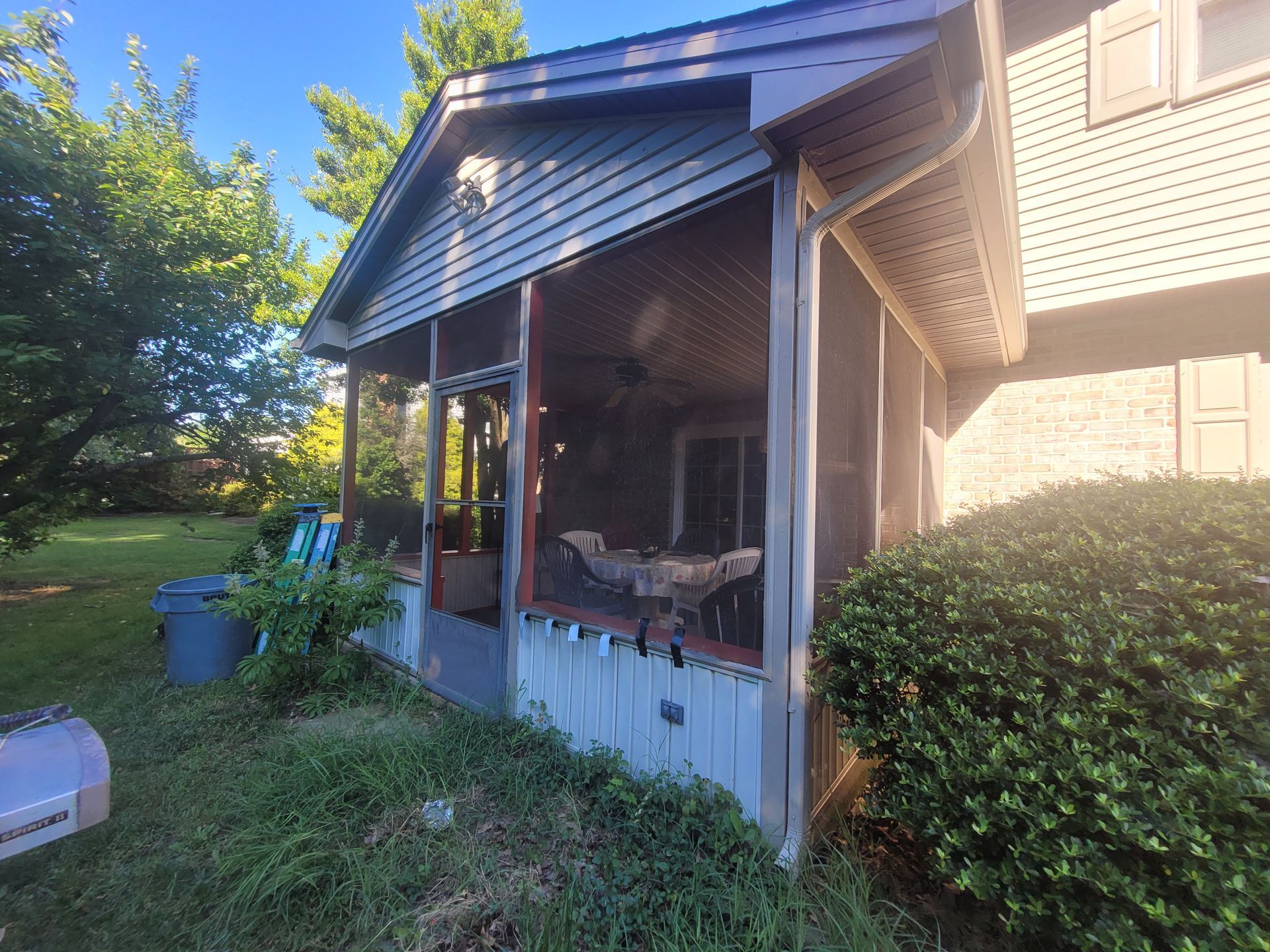 There is a screened in porch on the side of a house.