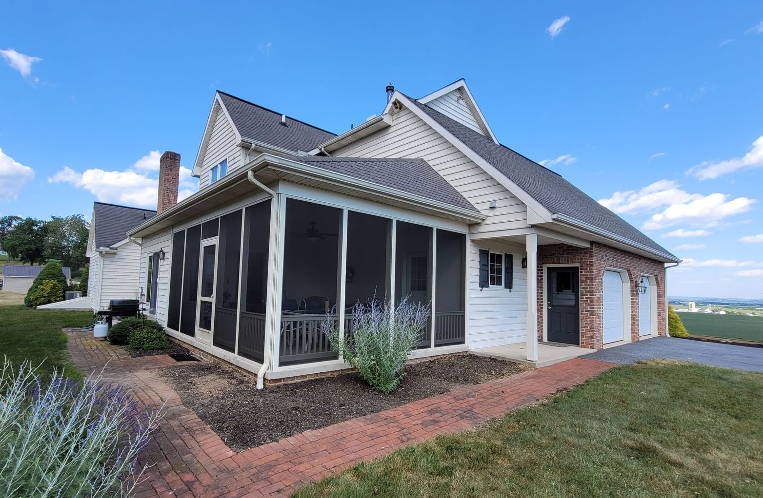 A large white house with a screened in porch and a garage.