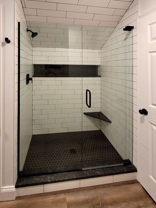 A bathroom with a walk in shower with a glass door.