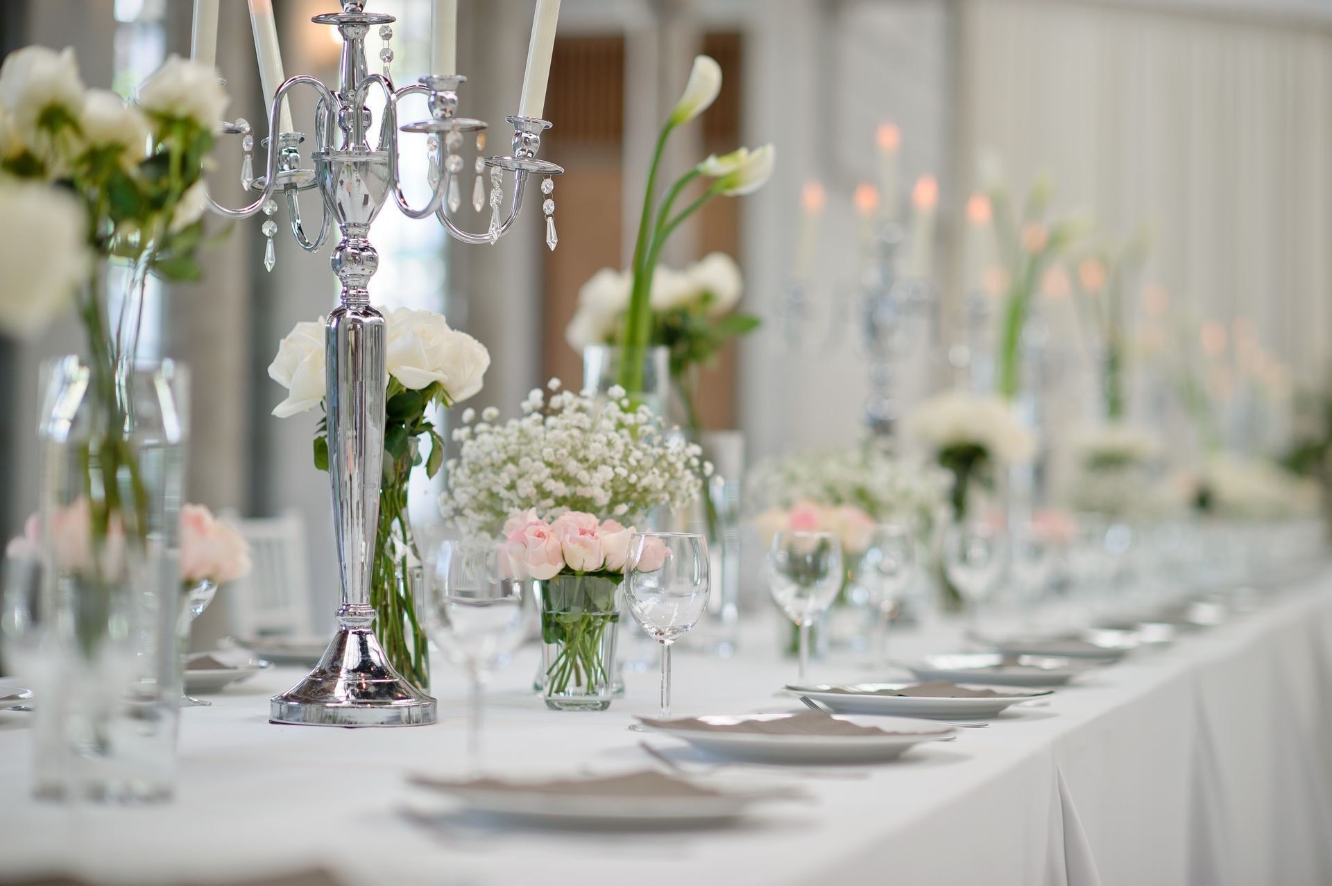 Elegant white wedding reception table with silver candelabras and pastel floral centerpieces