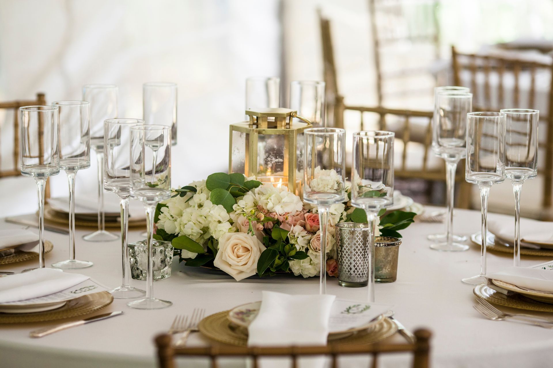 Elegant banquet table with white tablecloth, glassware, candles, and a floral centerpiece