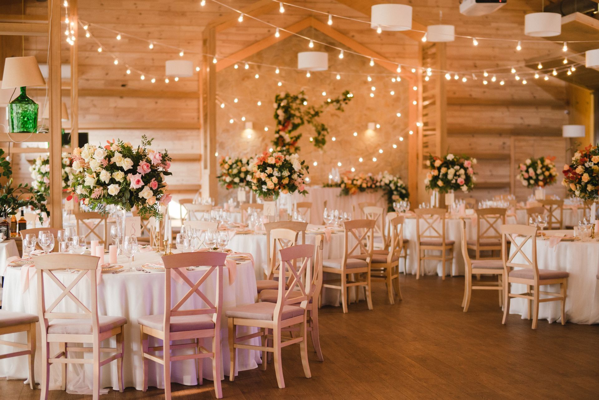 Elegant wedding reception hall with white chairs, floral centerpieces, and warm string lights