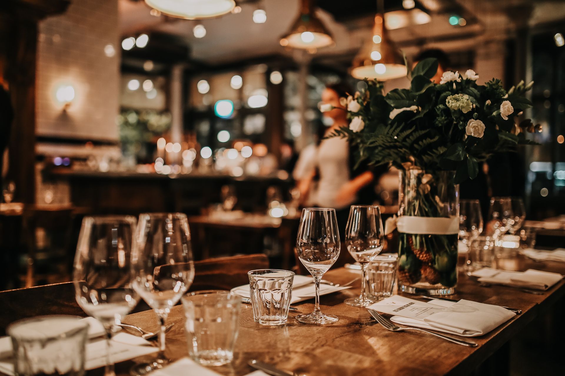 Elegant restaurant table set with wine glasses, candles, and a floral centerpiece in warm ambient light