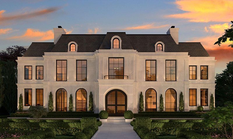Elegant two-story mansion with lit windows and a manicured front yard at sunset