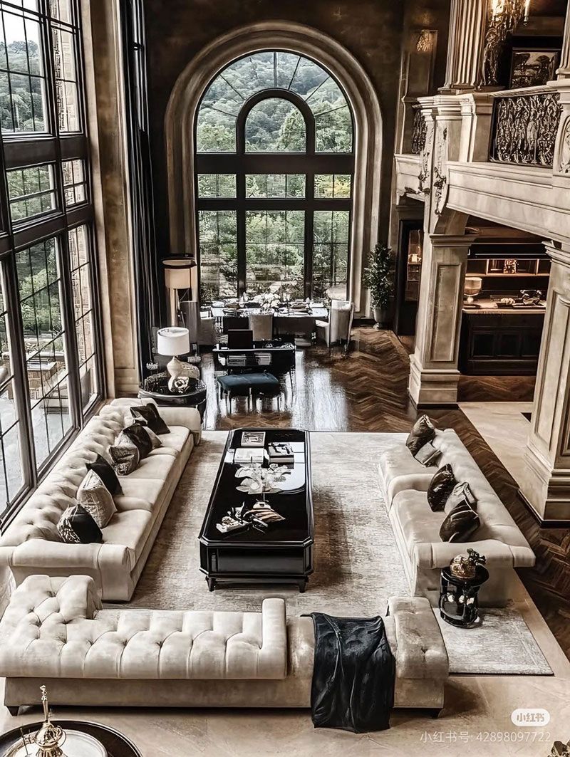 Luxurious living room with tall arched windows, white sectional sofas, and a fireplace