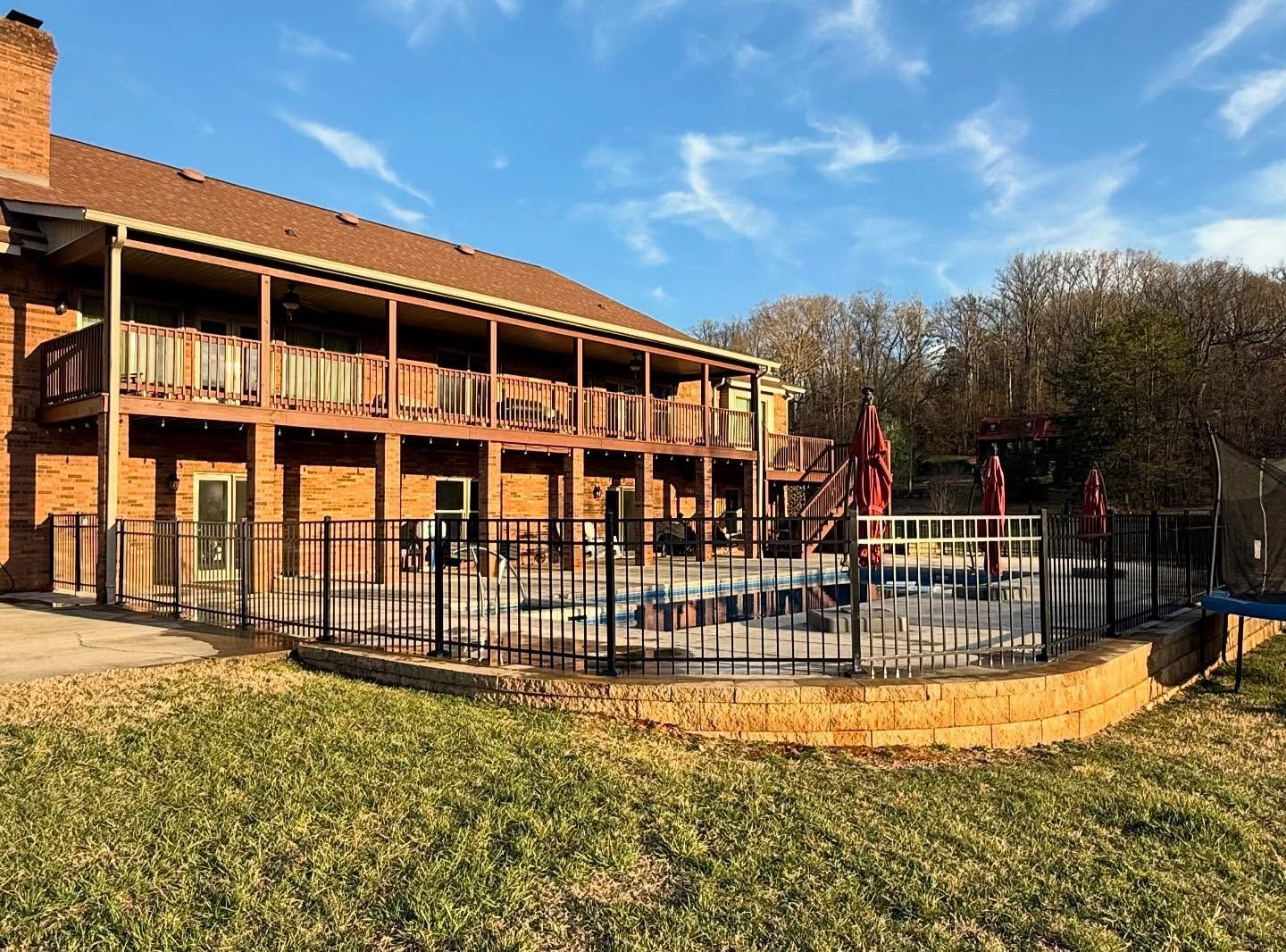 Apartment building with covered balconies and a fenced outdoor pool under a clear blue sky