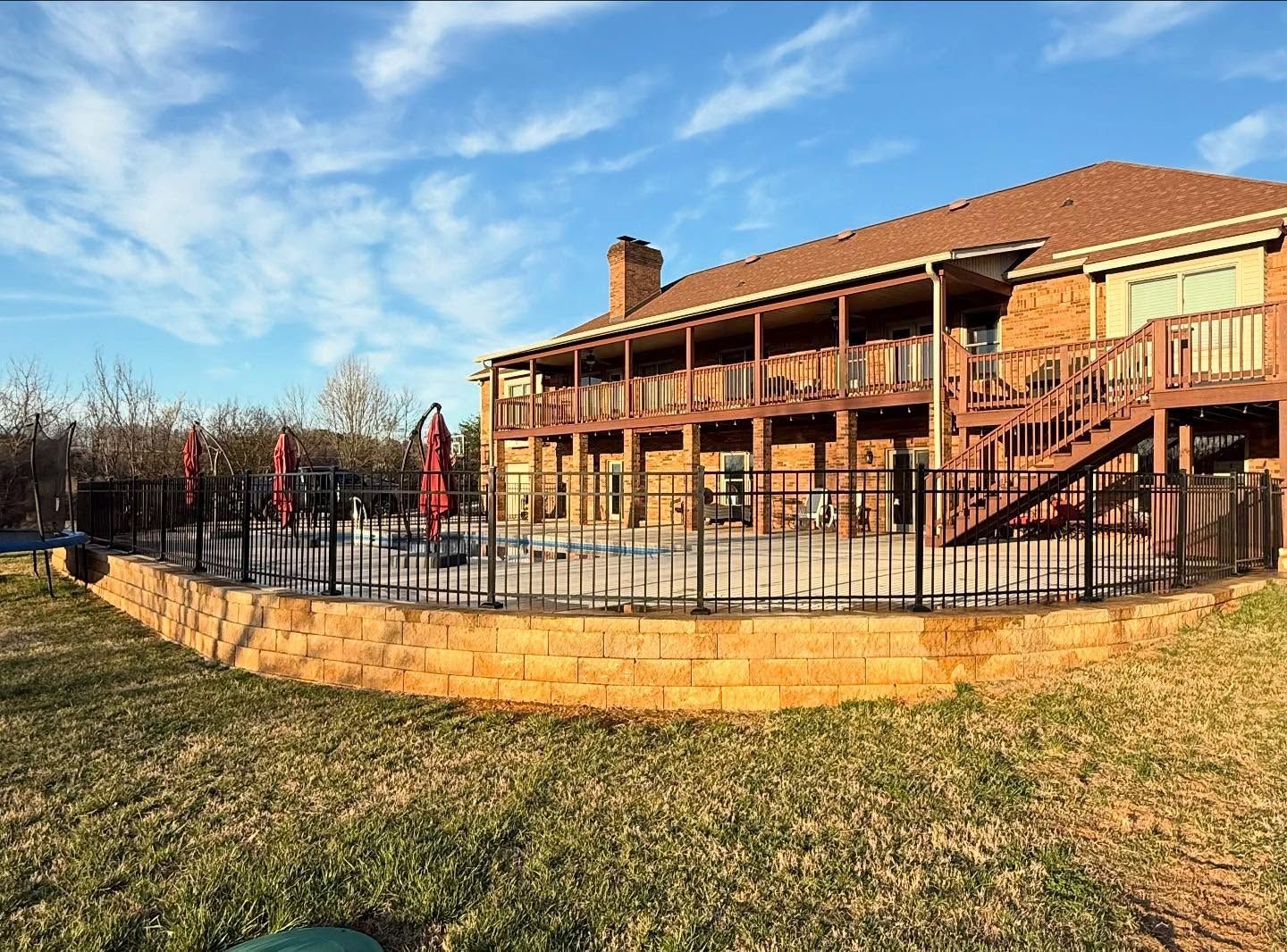 Two-story brick building with a fenced patio and staircases on a sunny day
