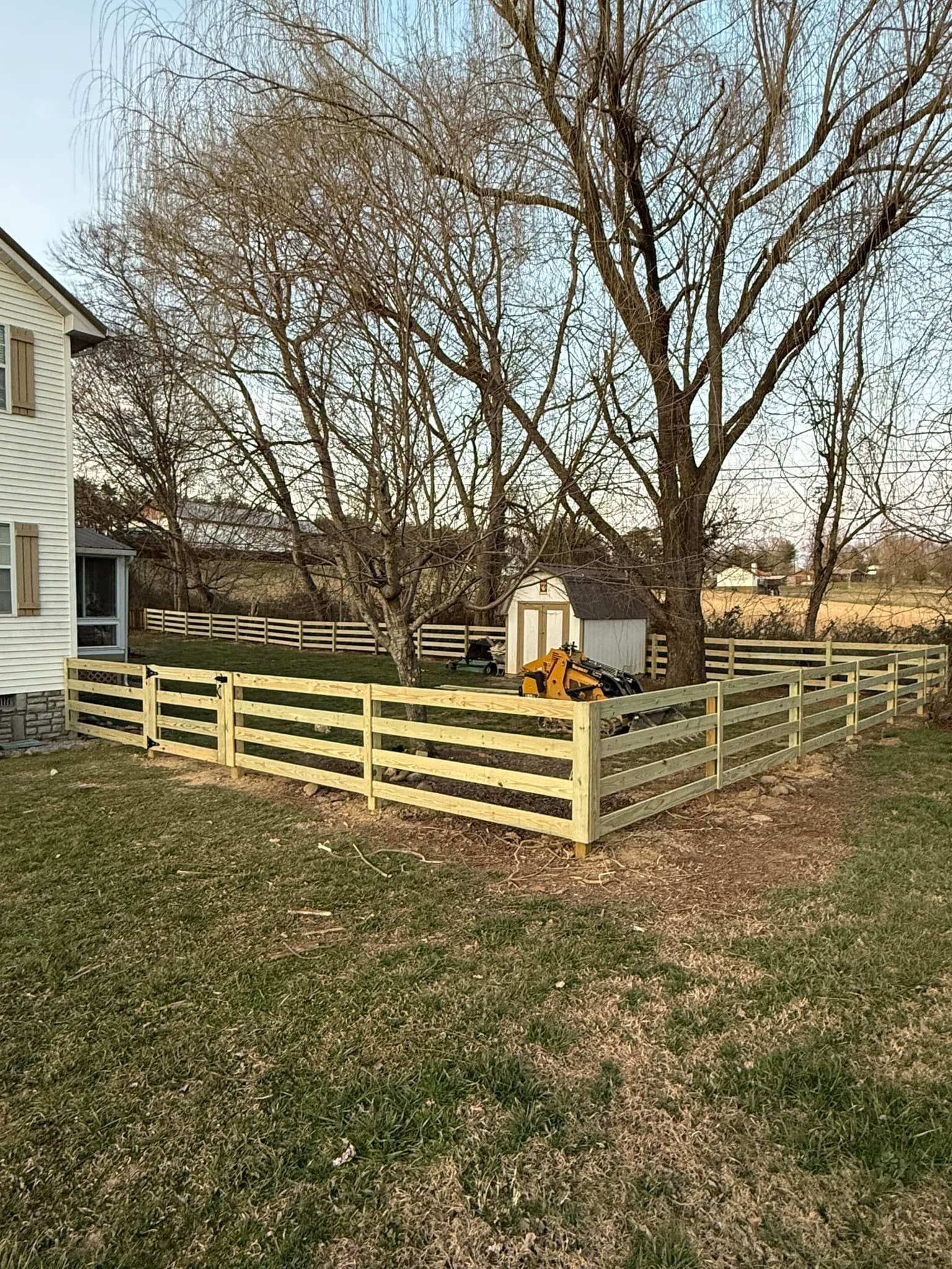 Backyard fenced garden with bare trees, a small shed, and a house at left in late fall.