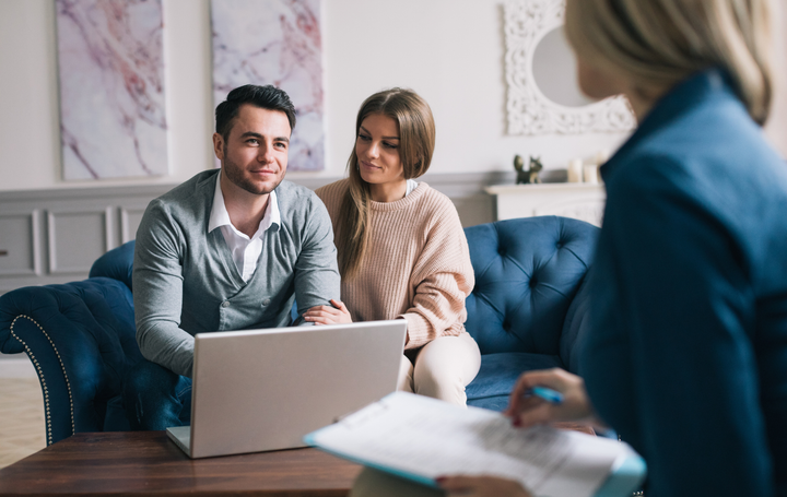 Two people consulting with a counselor in a bright office, with a laptop on the table.