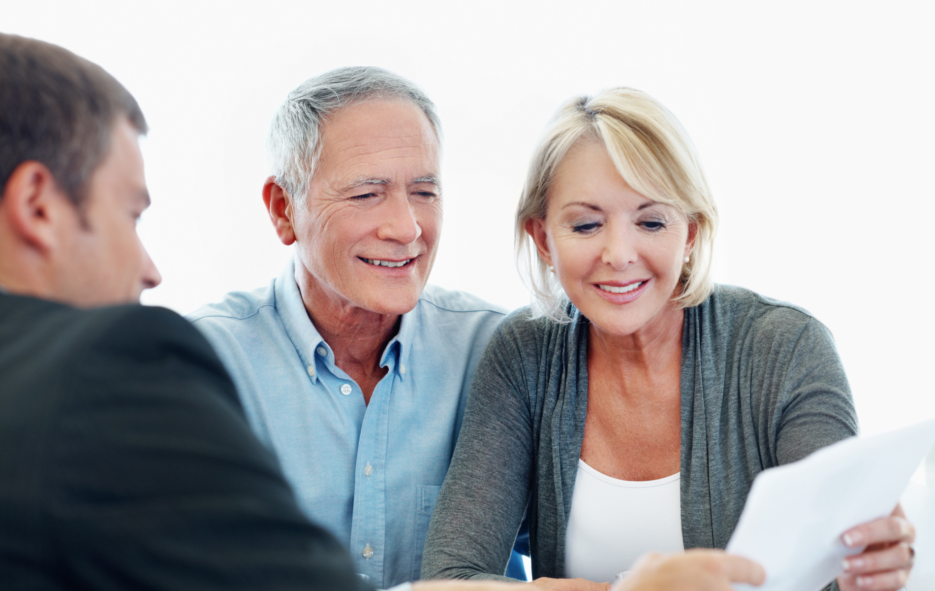 Three people smiling and reviewing a document together at a table