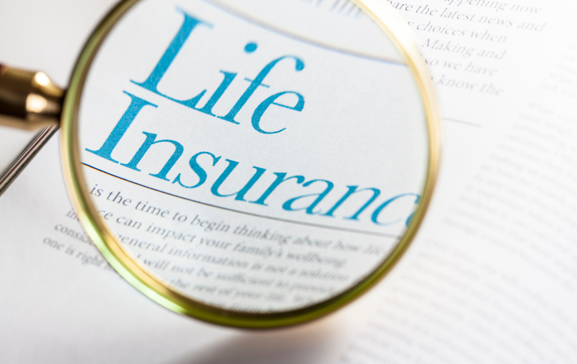 Magnifying glass over a life insurance document with blue text.