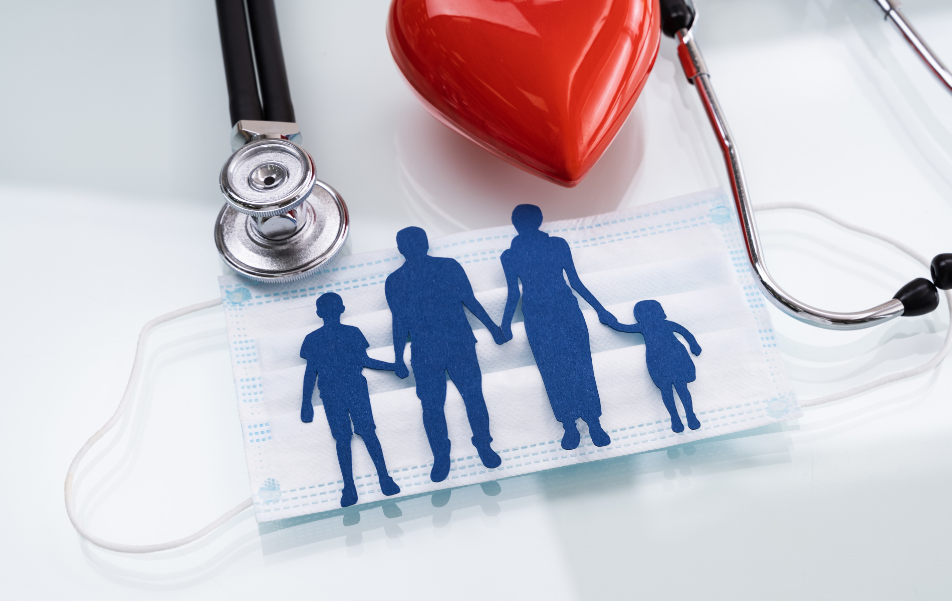Blue family silhouette on a clear puzzle piece beside a stethoscope and red heart