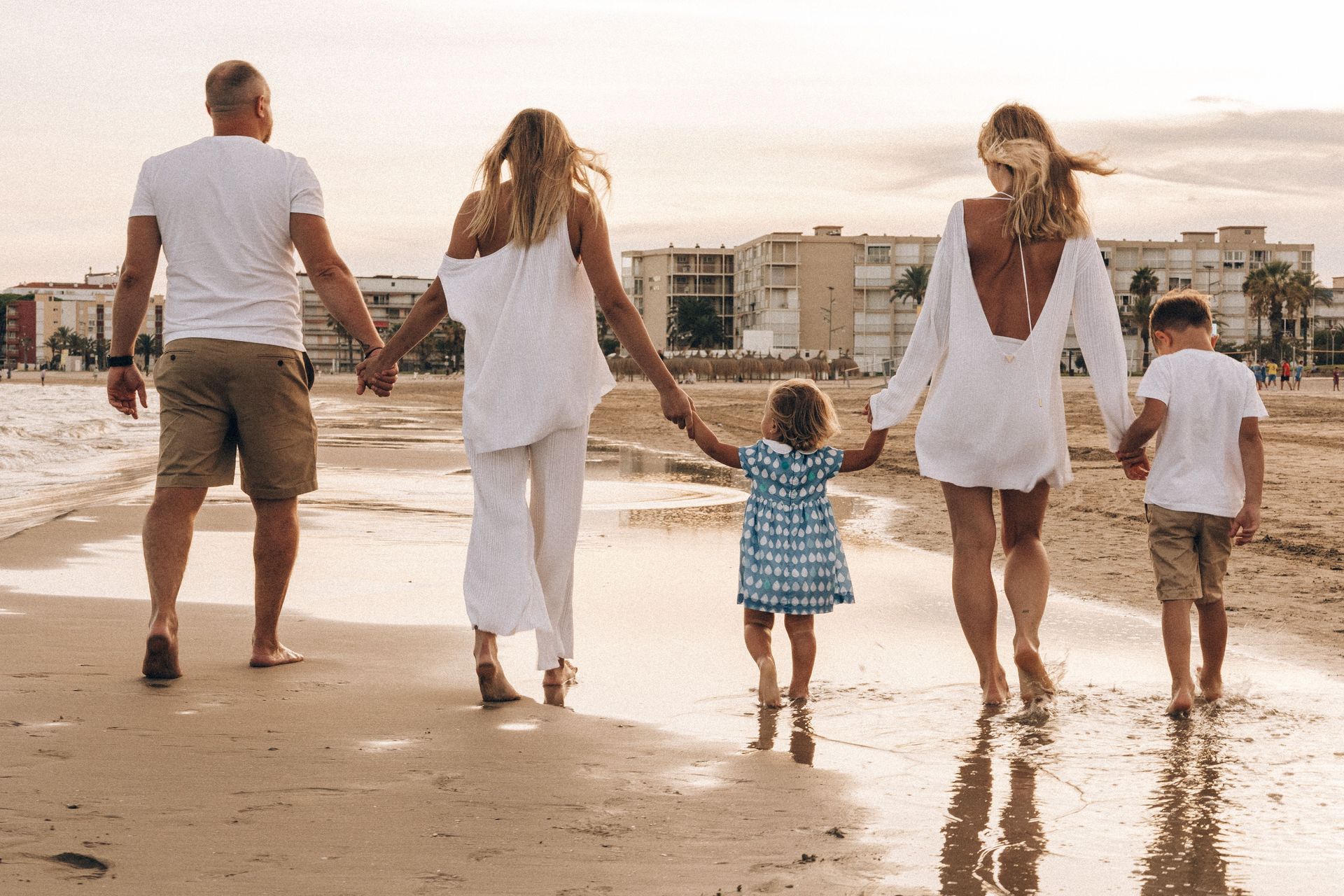 Family walking hand in hand along a beach at sunset
