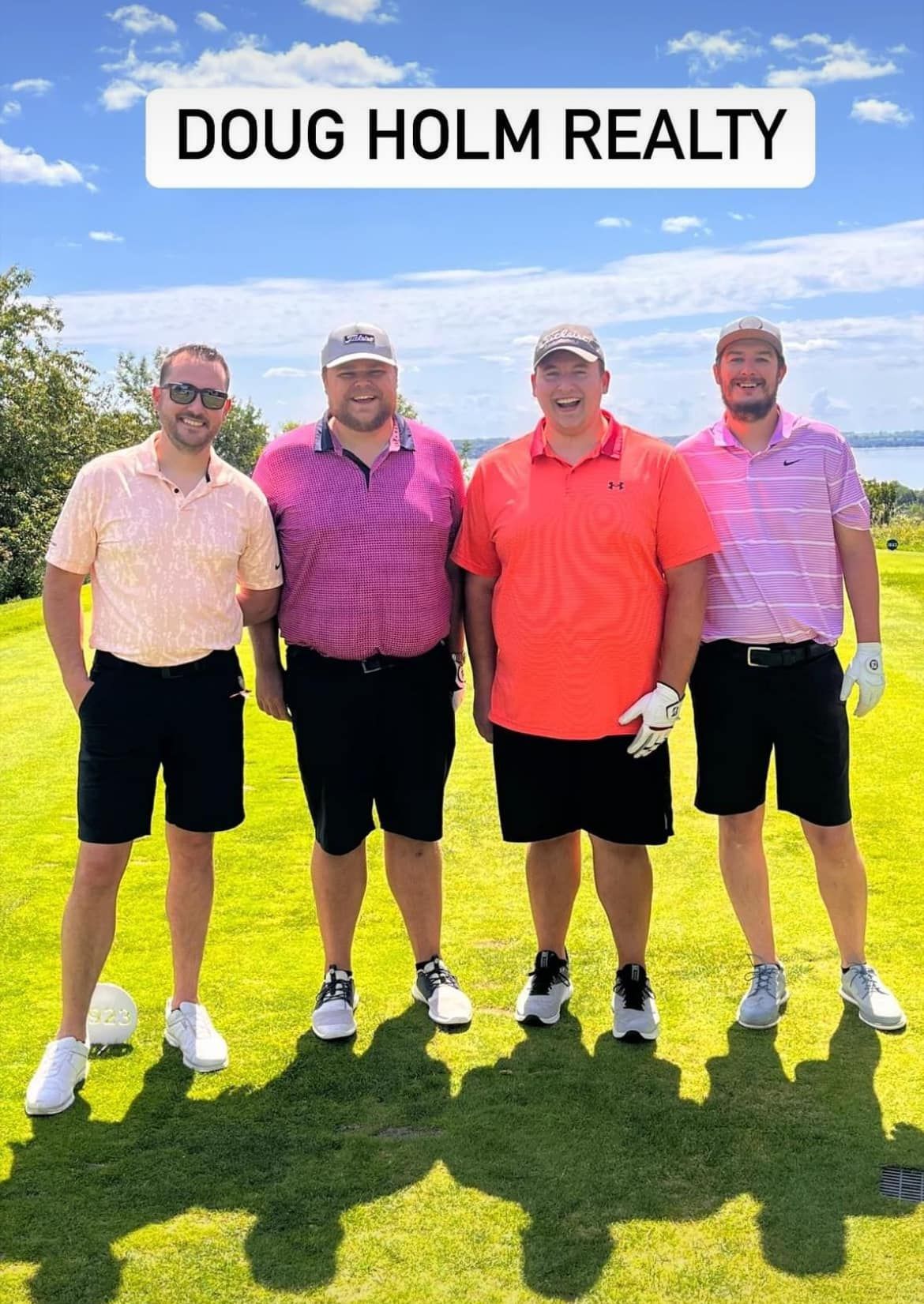 Four people wearing golf attire stand together outdoors on a sunny day with 