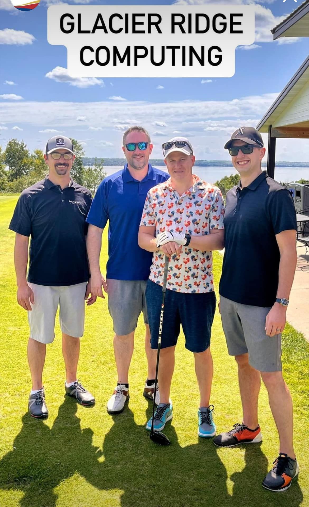 Four people stand on a grassy golf course, smiling in front of a lake under a blue sky, text reads 