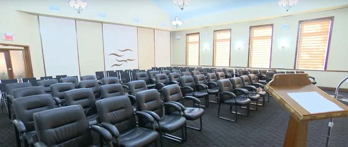 Une grande salle avec des rangées de chaises et un podium.
