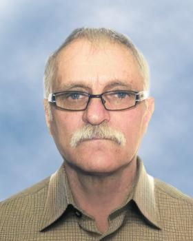 Un homme avec des lunettes et une moustache porte une chemise à carreaux.
