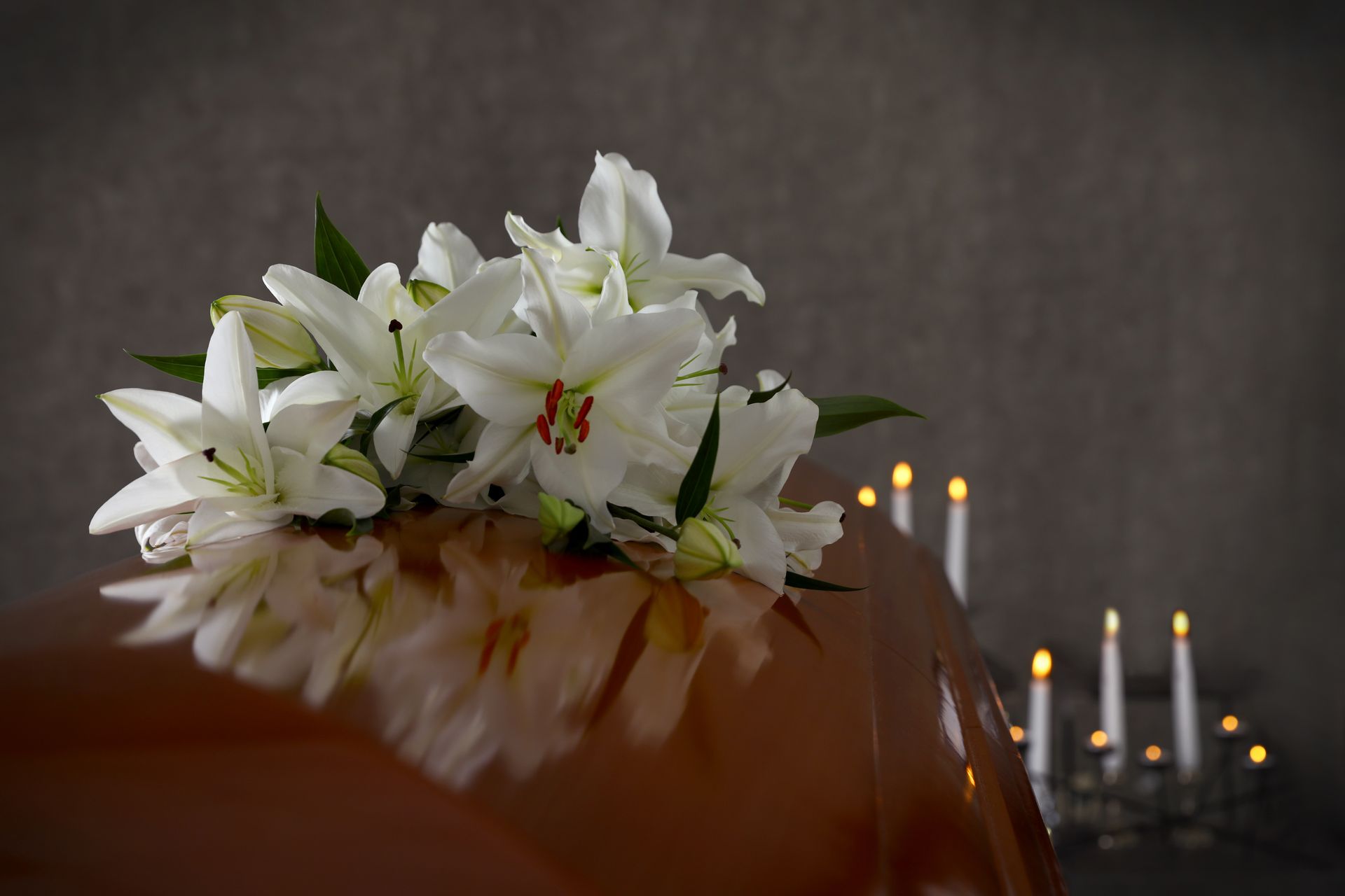 Un cercueil avec des lys blancs et des bougies dessus.
