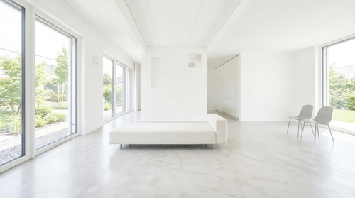 Helles, minimalistisches Schlafzimmer mit niedrigem, weißem Bett, großen Fenstern und zwei Stühlen an der Wand.