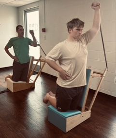 Men using Gratz Arm Chairs in a Duet Session. One man is a cyclist and one man is a Rugby player. Pilates for athletes.
