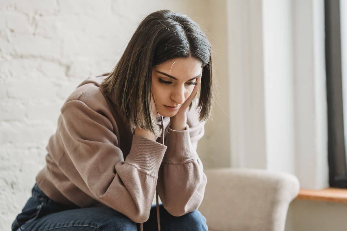 young woman looks down with head in hands