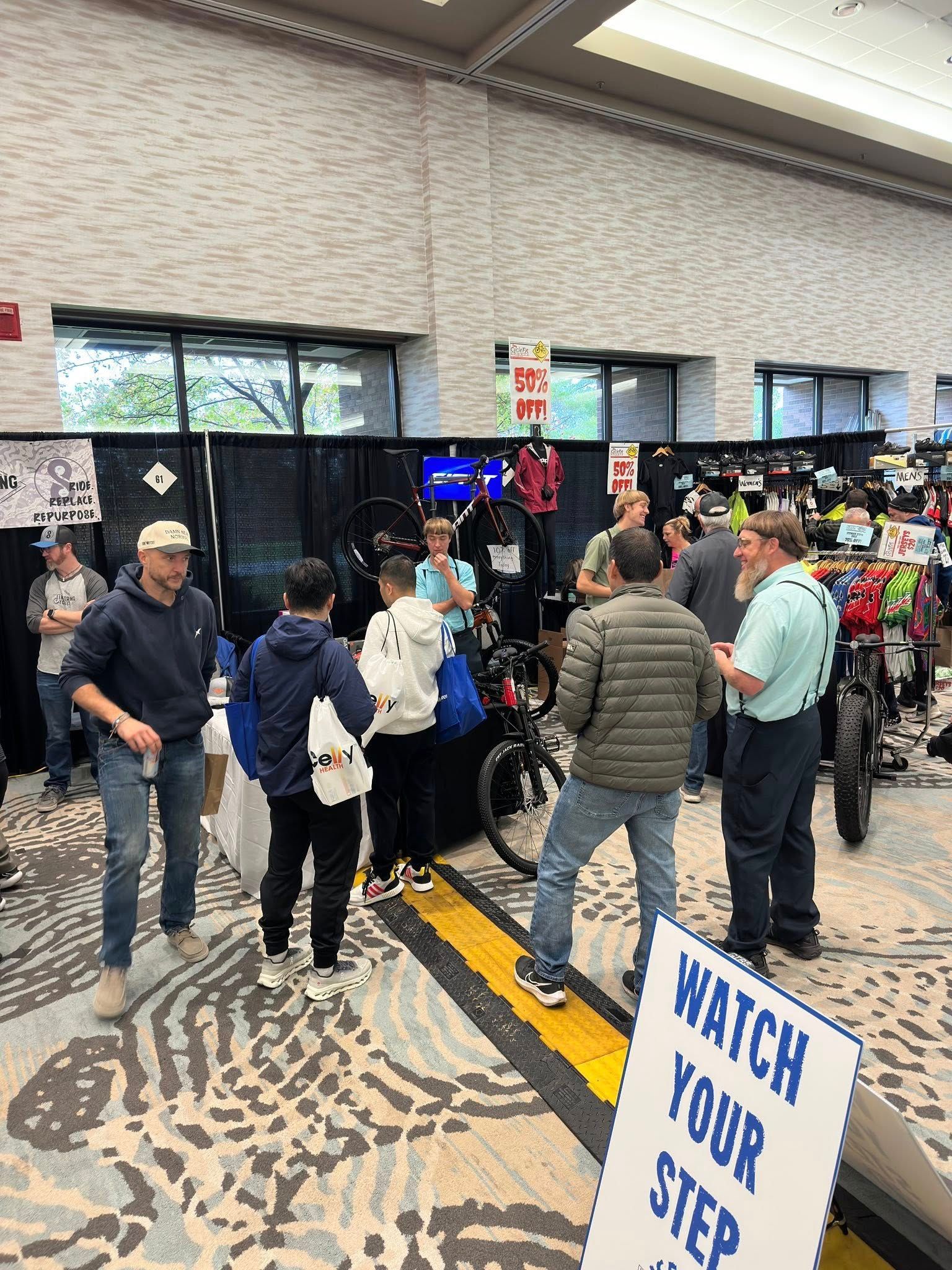 Attendees browse bicycles and gear at an indoor convention, with a