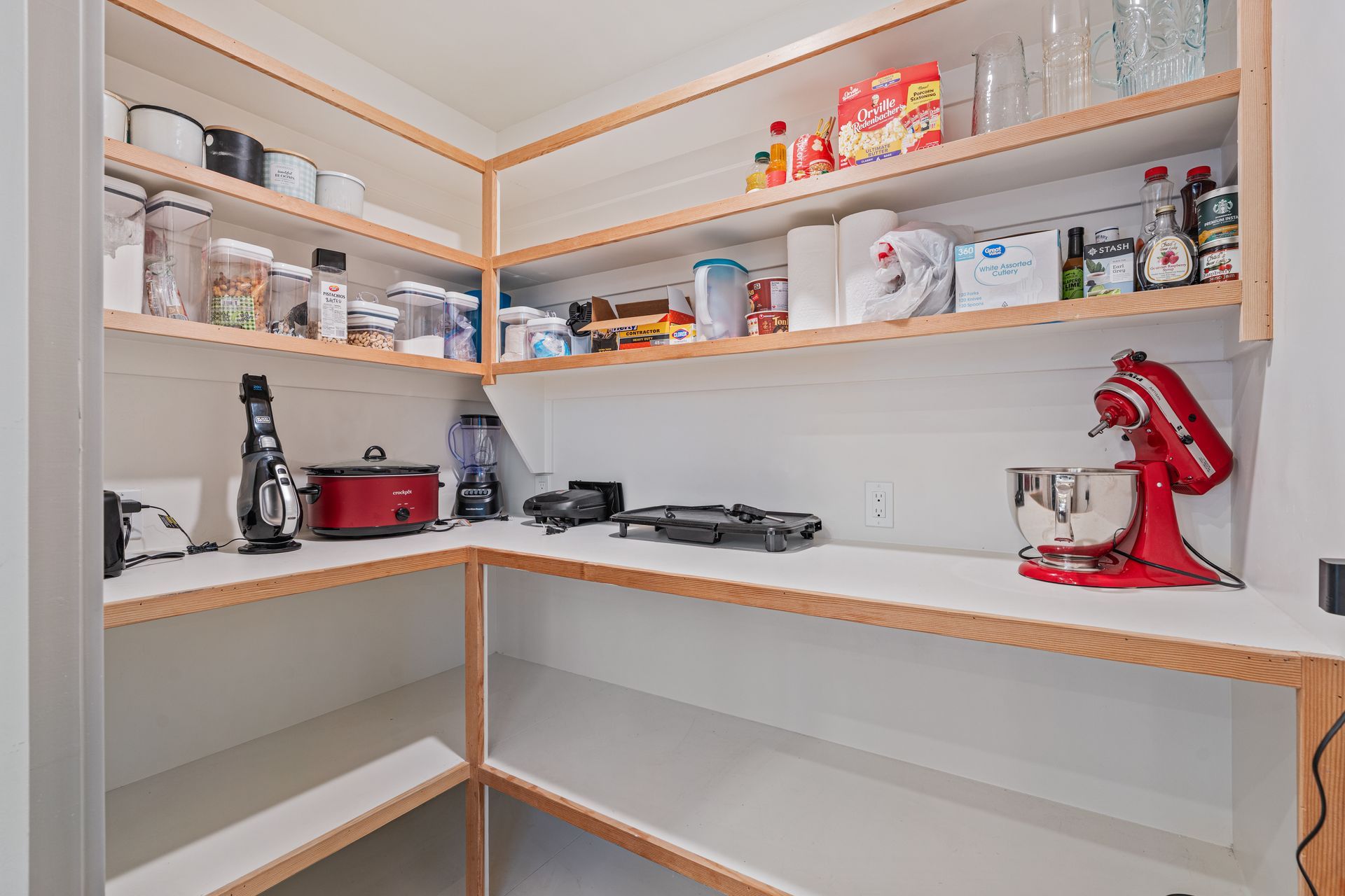 Pantry with white shelves, glassware, small appliances, and a red stand mixer on the right.