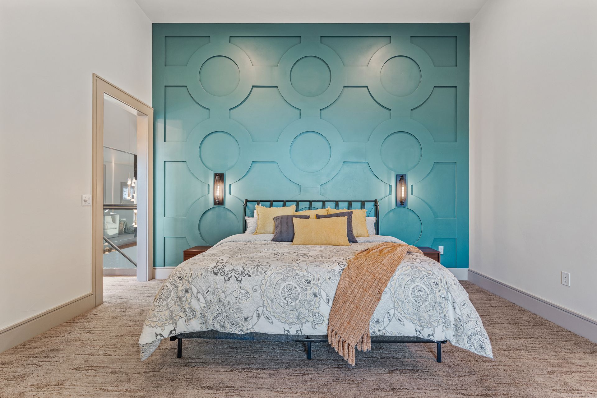 Bedroom with teal geometric accent wall, queen bed, and floor mirror.