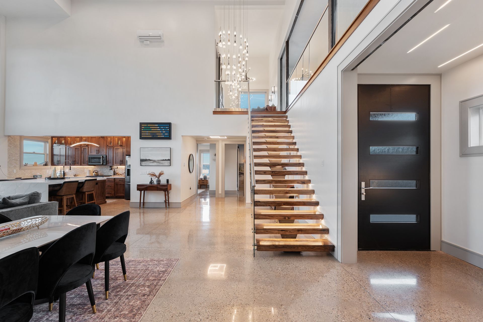 Modern open-concept interior with staircase, dining area, and kitchen with glossy floors