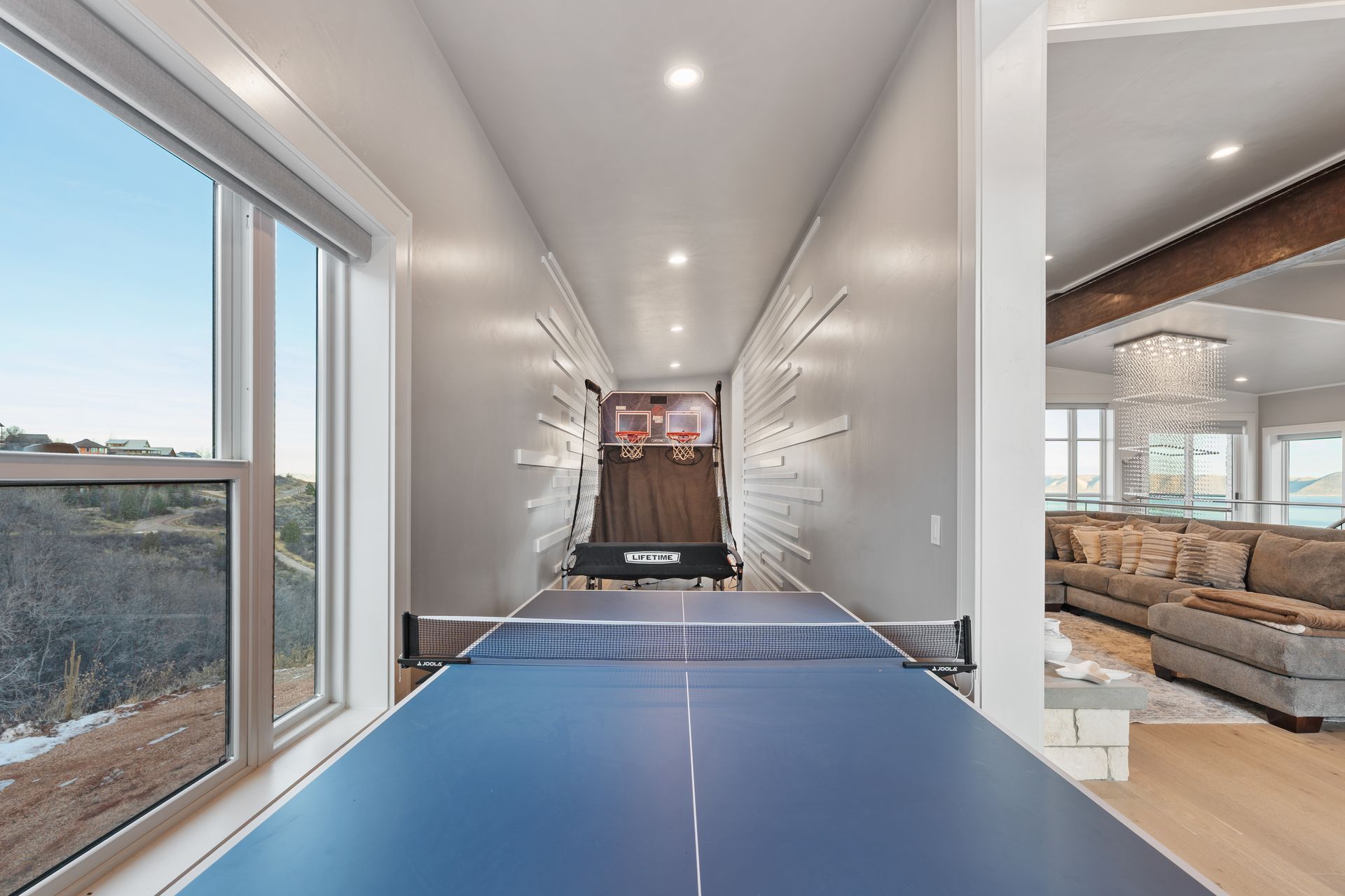 Bright hallway with a blue ping-pong table, large window, and a living room visible at the end.