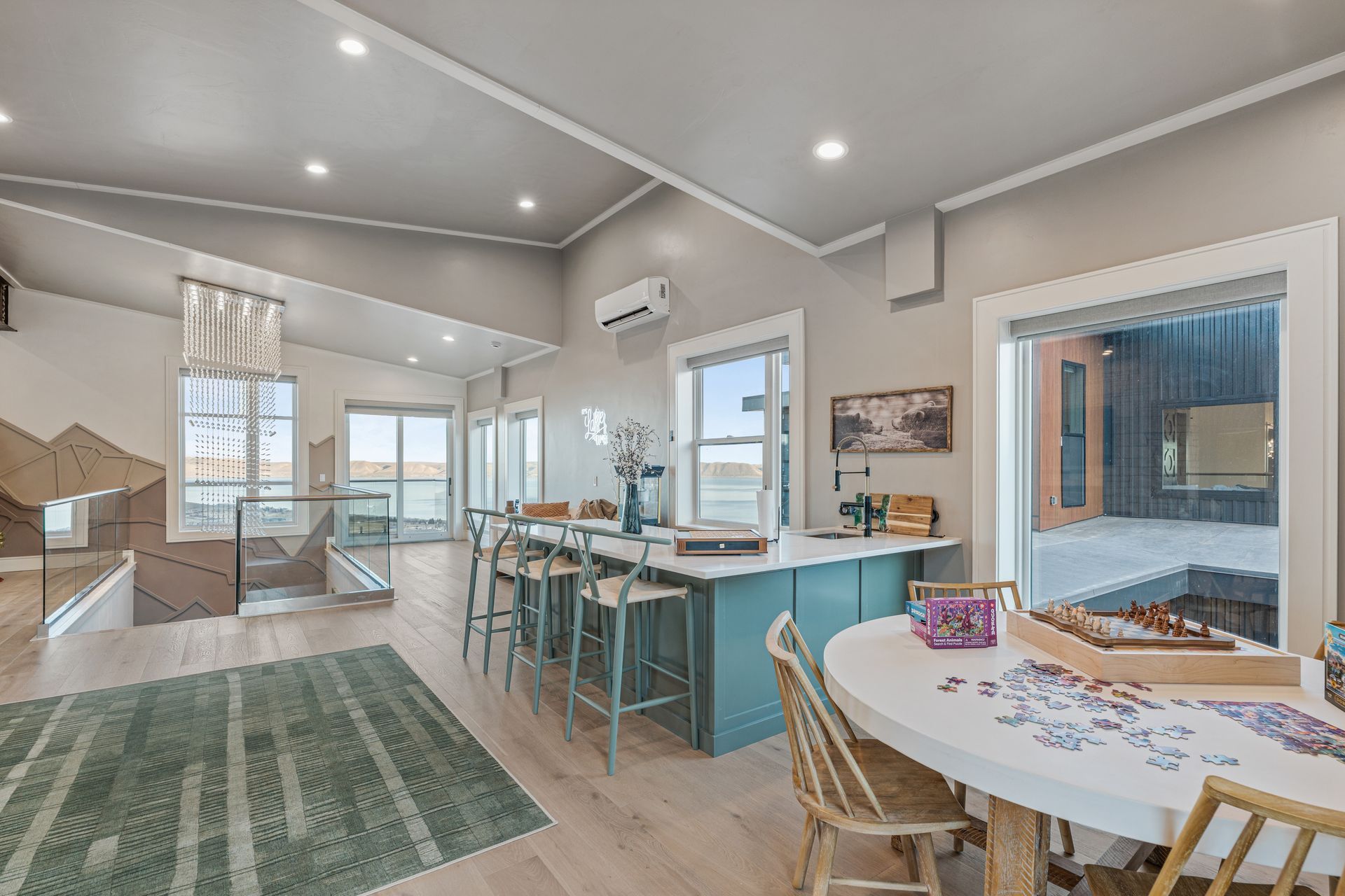 Bright open kitchen and dining area with turquoise island, bar stools, and sliding glass doors