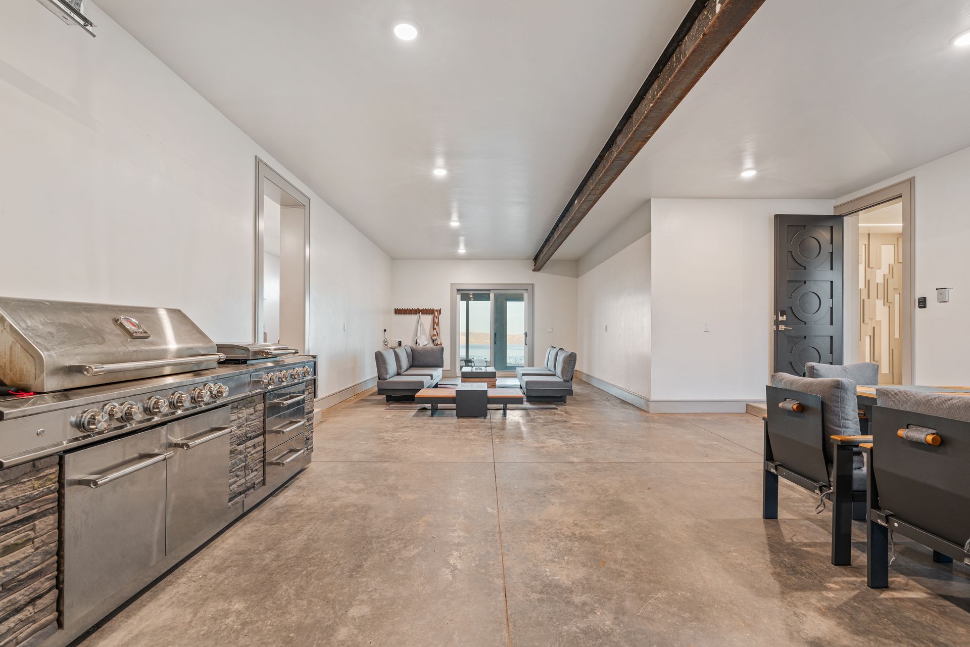 Modern indoor lounge with stainless grill on the left, concrete floor, and seating area at the far end