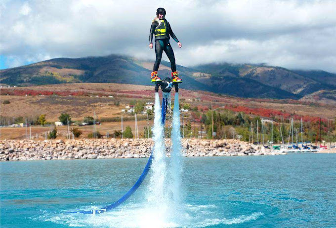 Person flyboarding above blue water with mountains in the background