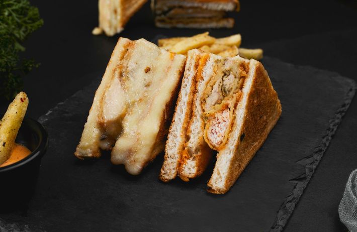Grilled sandwich with lettuce, tomato, and melted cheese on a hot grill, steaming