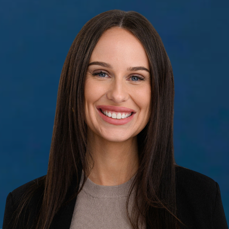 Smiling woman with long dark hair wearing a black blazer against a blue background