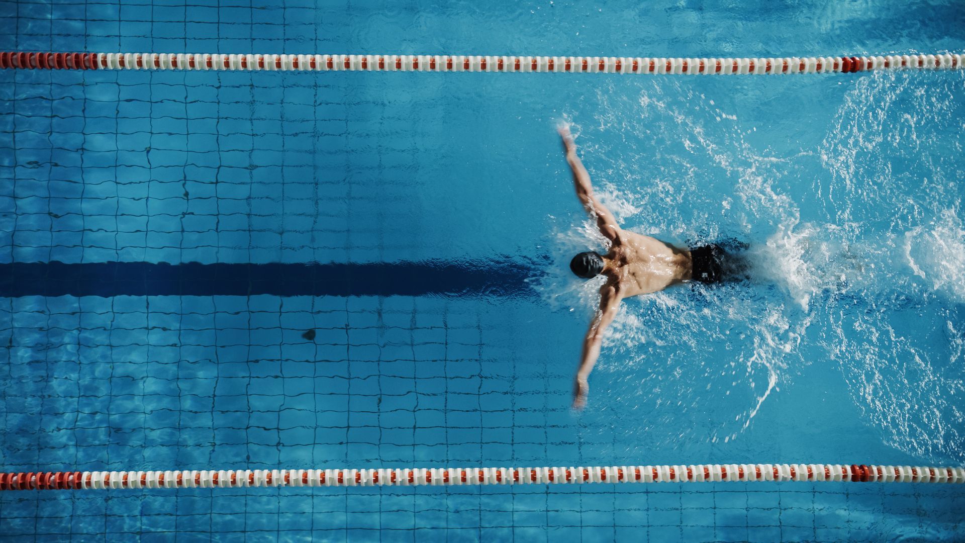 A man is swimming in a swimming pool.